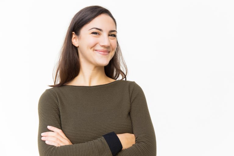 Happy cheerful female customer posing for camera with arms crossed. Young woman in casual standing isolated over white background. Happy woman concept